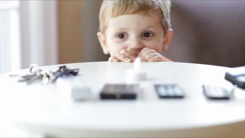 Child looking at remote controls on a table. 