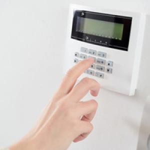 Hand entering pin number on alarm