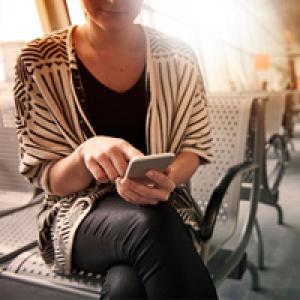 Woman sitting in airport using mobile phone