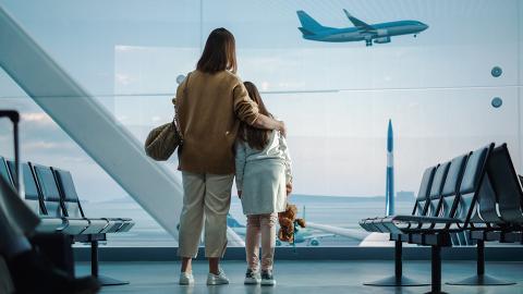 A woman and child watching planes leave from airport terminal